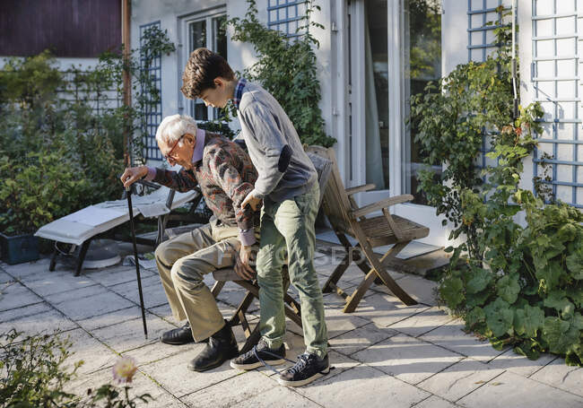 Garçon aider grand-père à se lever dans la cour arrière — Photo de stock
