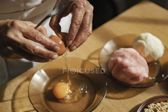 Жінка розбиває яйце в чаші на кухні. — стокове фото