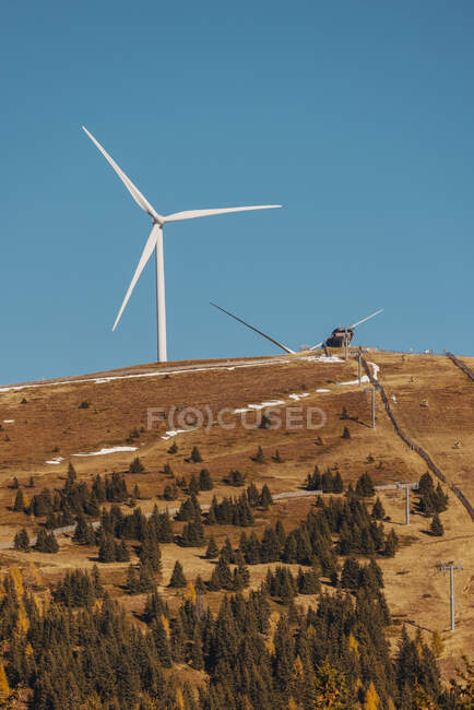 Cume de montanha de outono marrom com turbina eólica em pé contra o céu azul claro no fundo — Fotografia de Stock