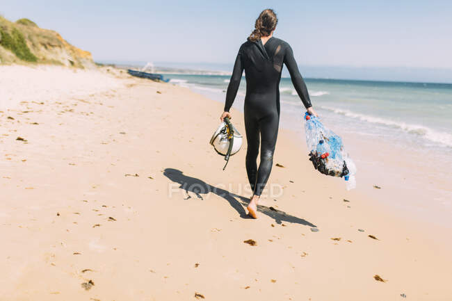 Эколог-мужчина с пластиковыми бутылками на песке на пляже — стоковое фото