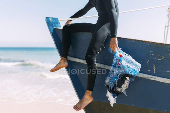 Jeune volontaire homme tenant un sac en filet sur le bateau — Photo de stock
