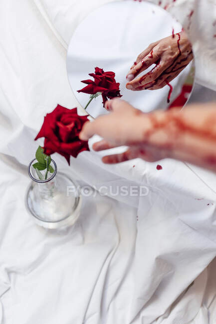 Woman touching rose with bleeding hand by mirror reflection — Stock Photo