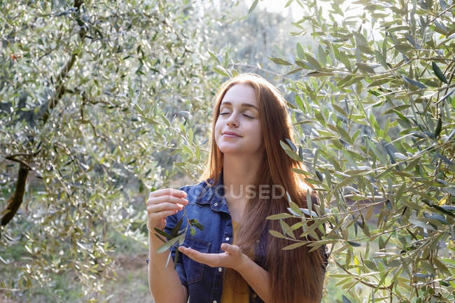 Junge Frau mit geschlossenen Augen inmitten von Bäumen auf dem Land — Stockfoto