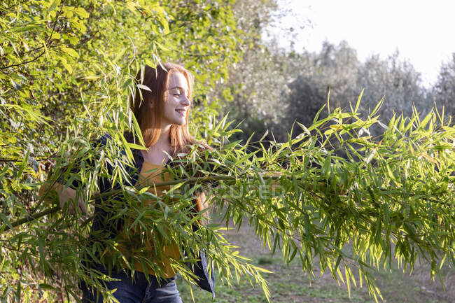Lächelnde junge Frau blickt auf Bambuspflanze — Stockfoto