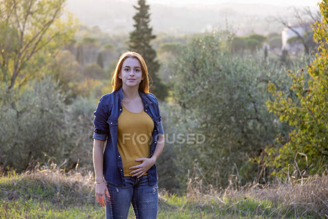 Smiling young woman standing at countryside — Stock Photo