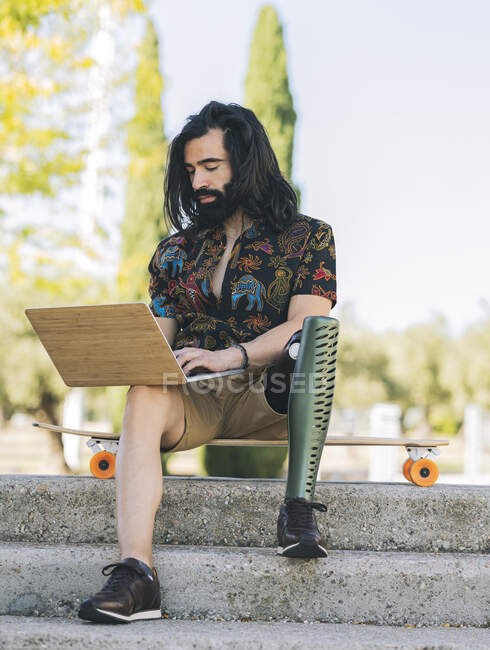 Hipster homme handicapé en utilisant un ordinateur portable sur les marches — Photo de stock