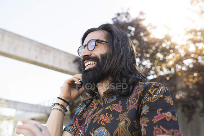 Hombre hipster feliz con la mano en el pelo en el parque - foto de stock