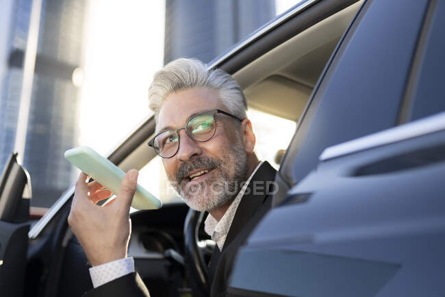 Homme d'affaires regardant loin parler sur le téléphone intelligent dans la voiture — Photo de stock