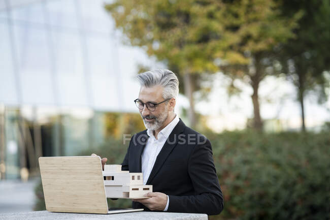 Uomo d'affari con occhiali in possesso di modello di casa — Foto stock