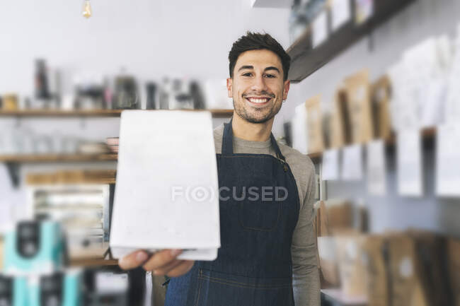 Smiling waiter holding credit card reader in cafe — Stock Photo
