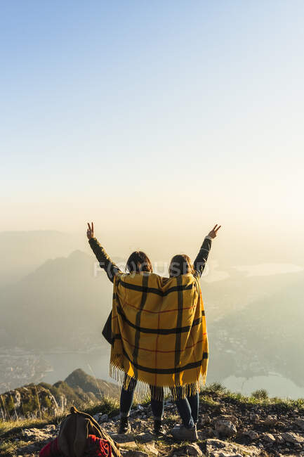 Mujeres jóvenes haciendo gestos en el pico de la montaña en Lecco, Italia - foto de stock