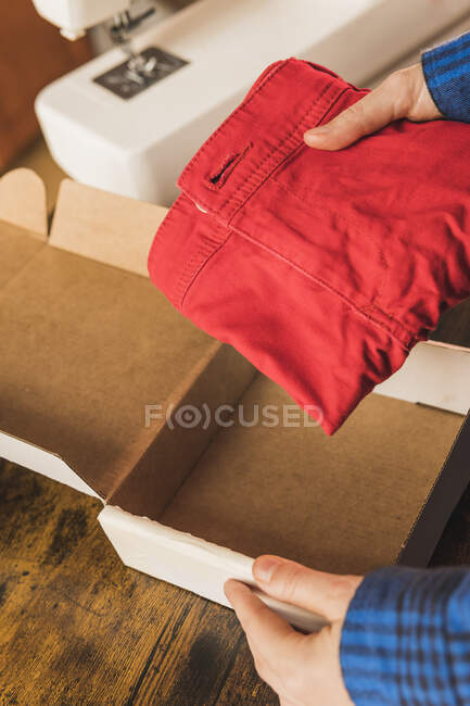 Femme couturière mettre des vêtements dans une boîte en carton — Photo de stock