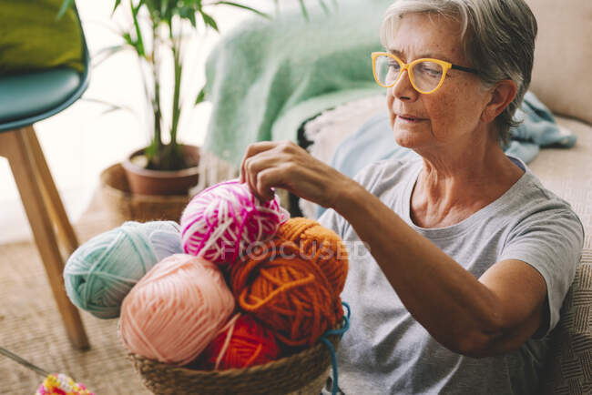 Donna che sceglie palla di lana dal cestino a casa — Foto stock