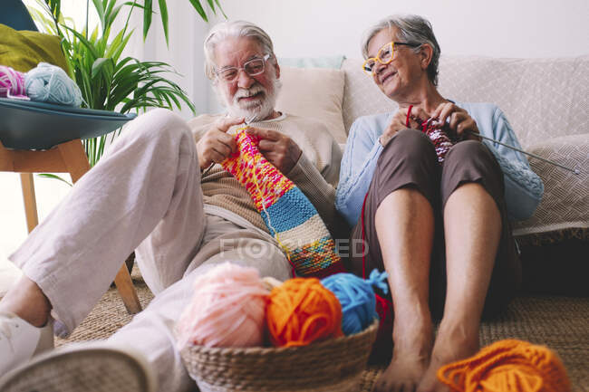 Senior couple with eyeglasses knitting wool at home — Stock Photo