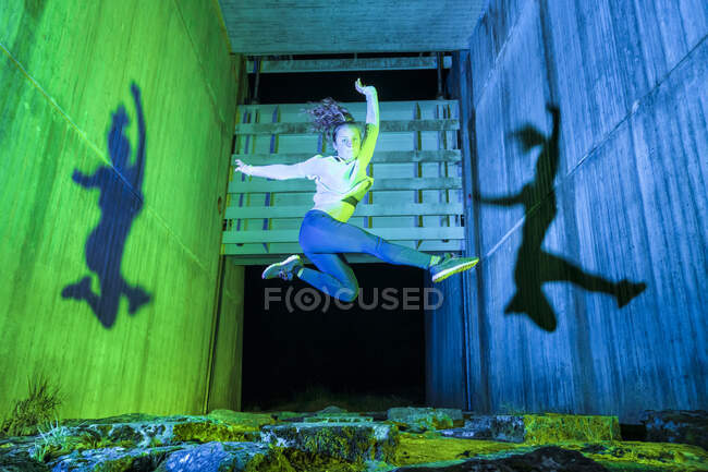 Despreocupada acróbata femenina saltando en medio de la pared - foto de stock