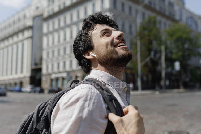 Счастливый человек с рюкзаком смотрит вверх по городу — стоковое фото