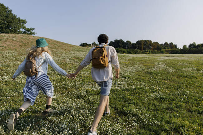 Man holding hand of girlfriend running on meadow — Stock Photo