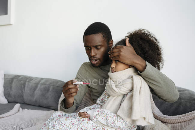 Padre preocupado comprobando la temperatura de la hija a través del  termómetro en casa — chica, padre que se queda en casa - Stock Photo |  #528463224