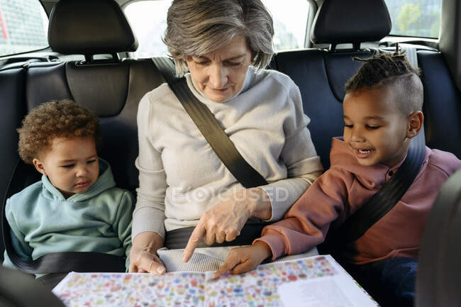 Nonna che legge libro con nipoti in auto — Foto stock