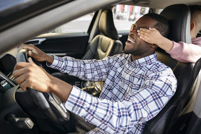 Figlio giocoso che copre gli occhi del padre in auto — Foto stock