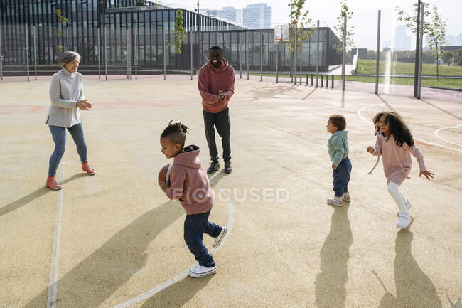 Sorrindo família jogando com basquete no campo de esportes — Fotografia de Stock