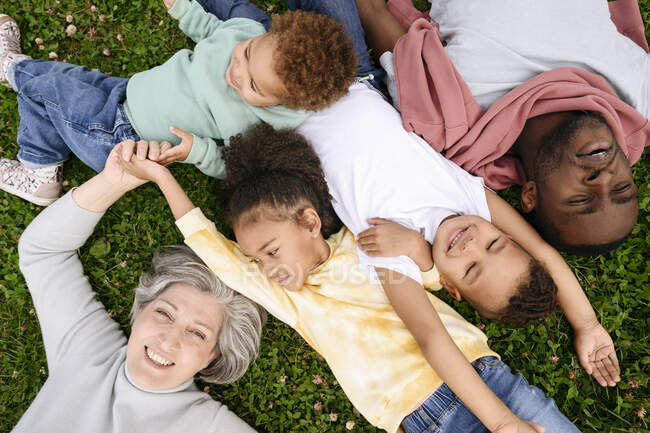 Sonriente familia acostada en el césped en el parque - foto de stock