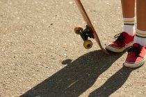 Женские ноги в коленных носках со скейтбордом — стоковое фото