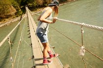 Woman walking on hanging footbridge — Stock Photo