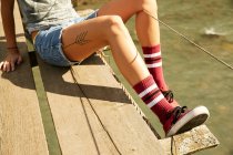 Female tattooed legs on footbridge — Stock Photo