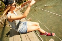 Frau sitzt auf Hängebrücke — Stockfoto
