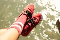 Pieds féminins en chaussettes de genou et baskets rouges — Photo de stock