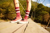 Female legs in knee socks and red sneakers — Stock Photo