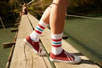 Pés femininos em meias de joelho e tênis vermelho — Fotografia de Stock