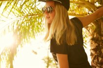 Donna in posa sulla spiaggia con palma — Foto stock