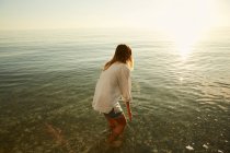 Жінка стоїть у воді на пляжі — стокове фото