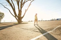 Donna che cavalca sullo skateboard nel parcheggio — Foto stock