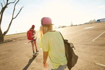 Frauen fahren mit Rucksäcken auf Skateboard — Stockfoto
