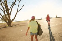 Women riding on skateboard with backpacks — Stock Photo