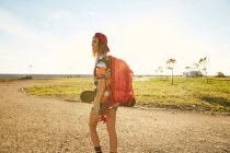 Женщина ходит с рюкзаком и скейтбордом — стоковое фото