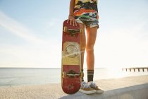 Женщина держит скейтборд на берегу моря — стоковое фото