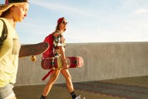 Frauen laufen mit Rucksäcken und Skateboards — Stockfoto