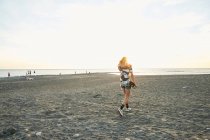 Femme tenant skateboard sur la plage — Photo de stock