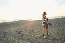 Frau mit Skateboard am Strand — Stockfoto