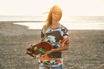 Woman holding skateboard on beach — Stock Photo