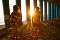 Donne che camminano sulla spiaggia vicino a colonne — Foto stock