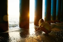 Donna seduta vicino a colonne sulla spiaggia — Foto stock