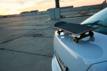 Скейтборд на багажнику автомобіля на заході сонця — стокове фото