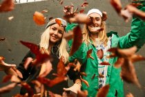 Amigas posando con hojas de otoño - foto de stock