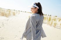 Женщина в козырьке прогулка по пляжу — стоковое фото