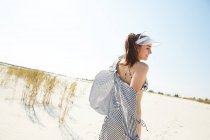 Mulher em viseira andando na praia — Fotografia de Stock